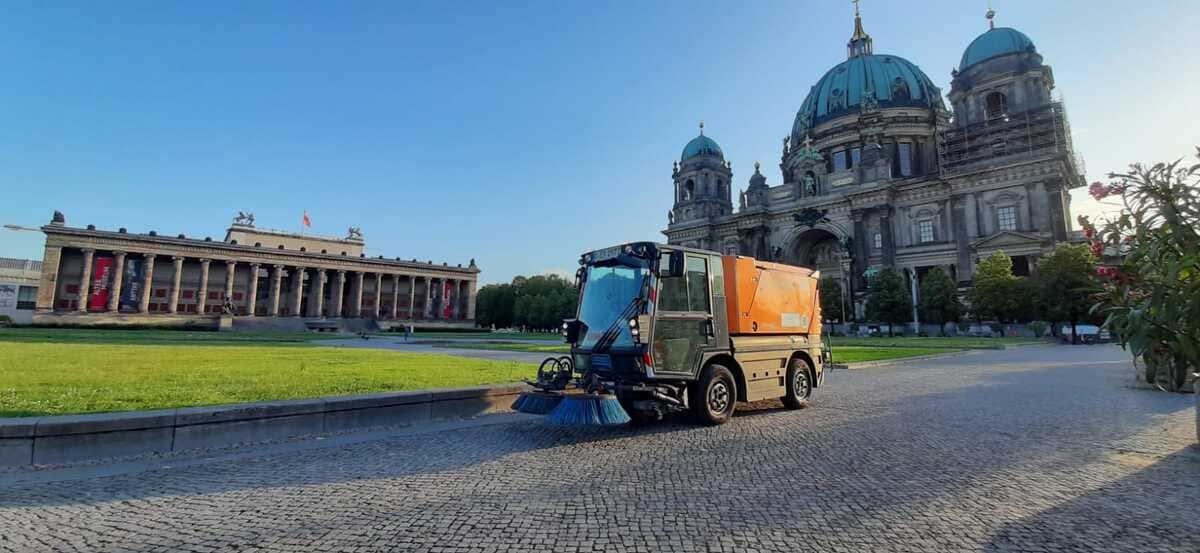 Orangefarbene Kehrmaschine auf einem Platz vor dem Berliner Dom.
