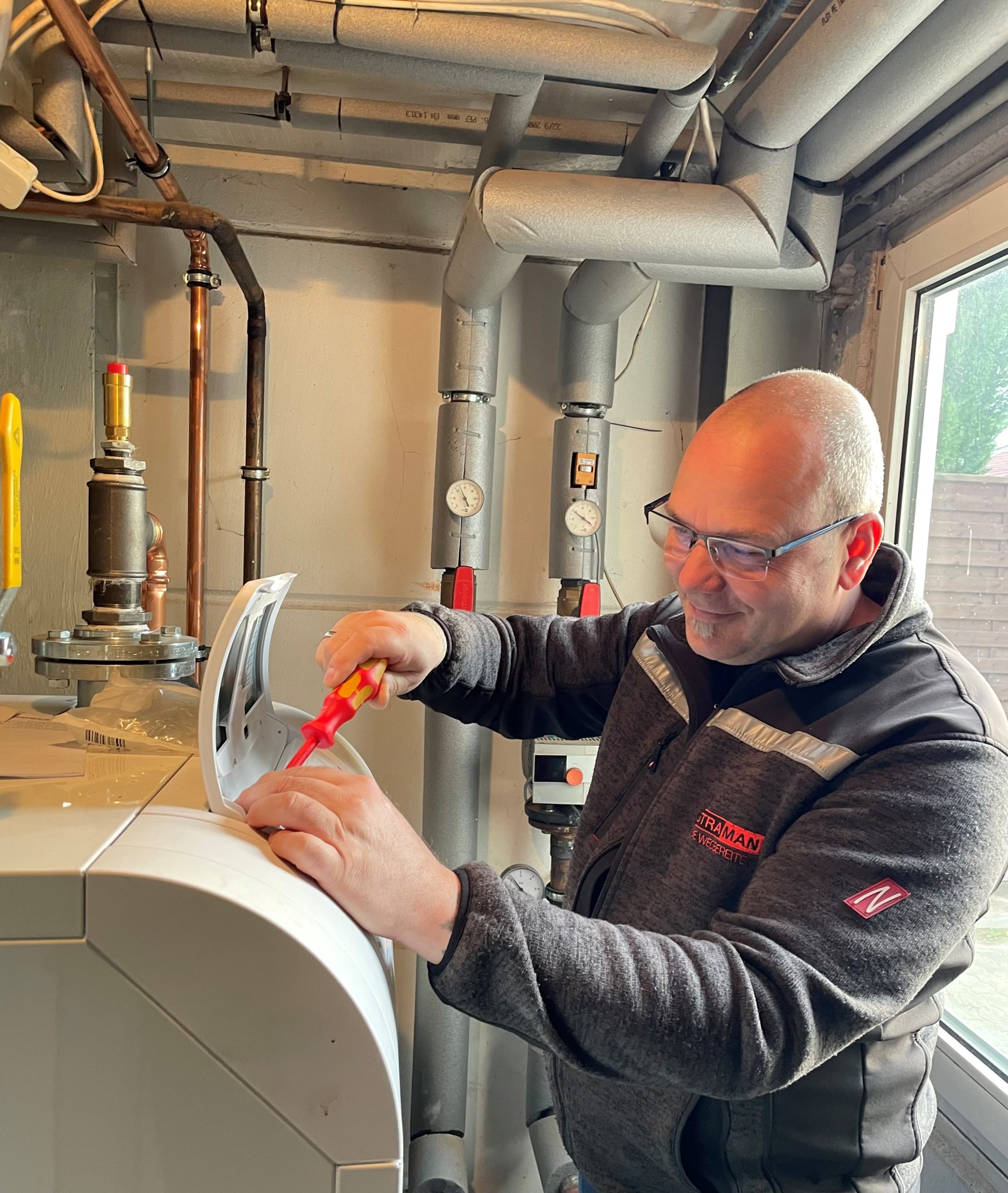 Servicetechniker bei der Wartung einer Heizungsanlage im Rahmen des technischen Gebäudemanagements.